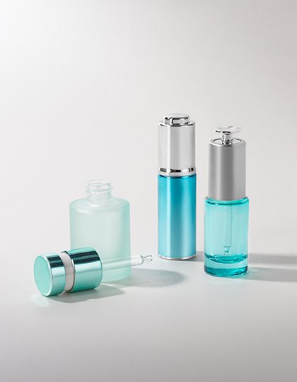 Collection of various push-button droppers with different finishes and container sizes, displayed on a grey background.